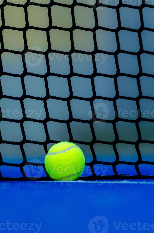 a ball at the foot of the net of a paddle tennis court with the background out of focus, racket sport background concept photo
