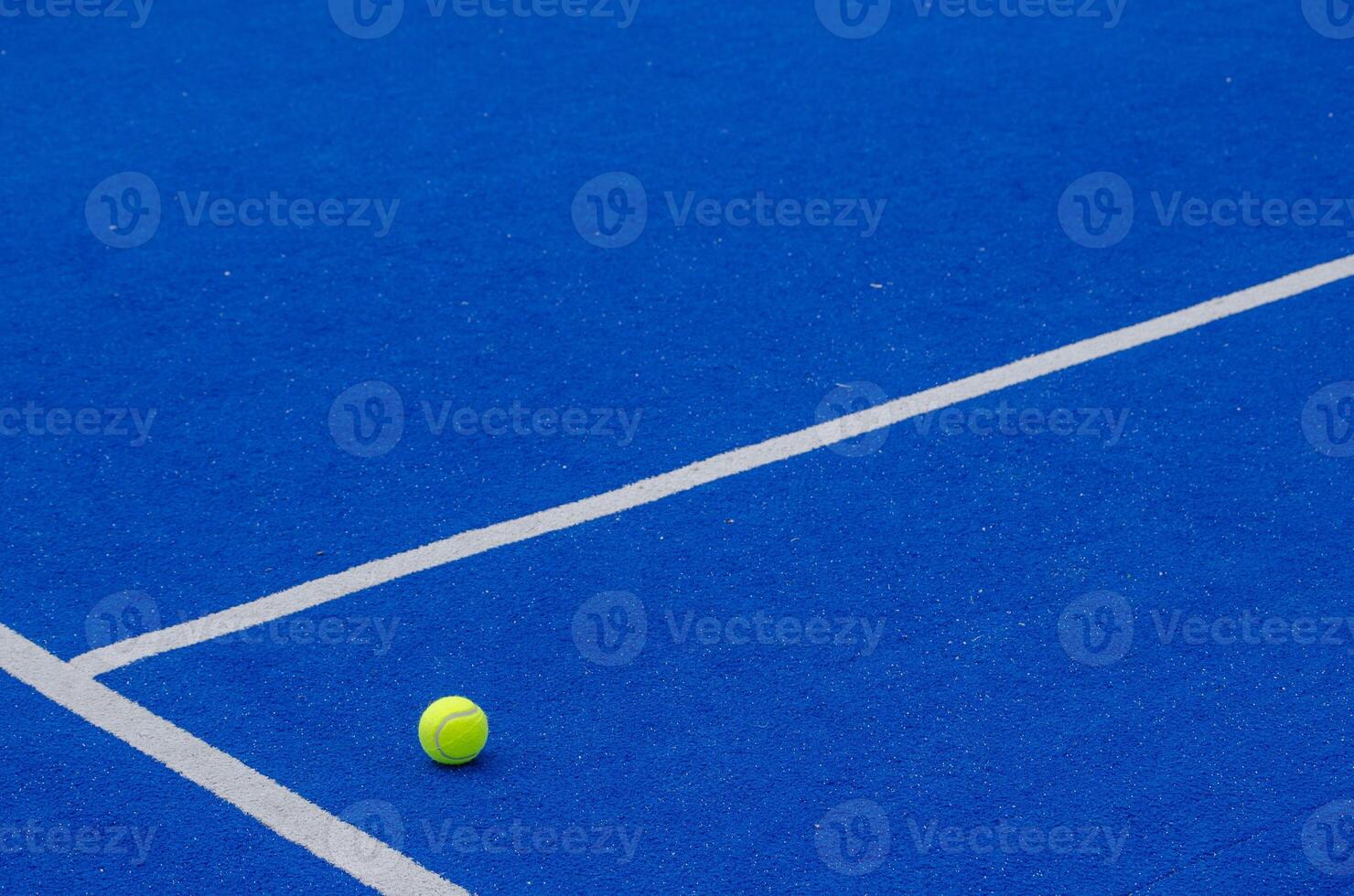 A ball on a blue paddle tennis court, racket sports concept photo