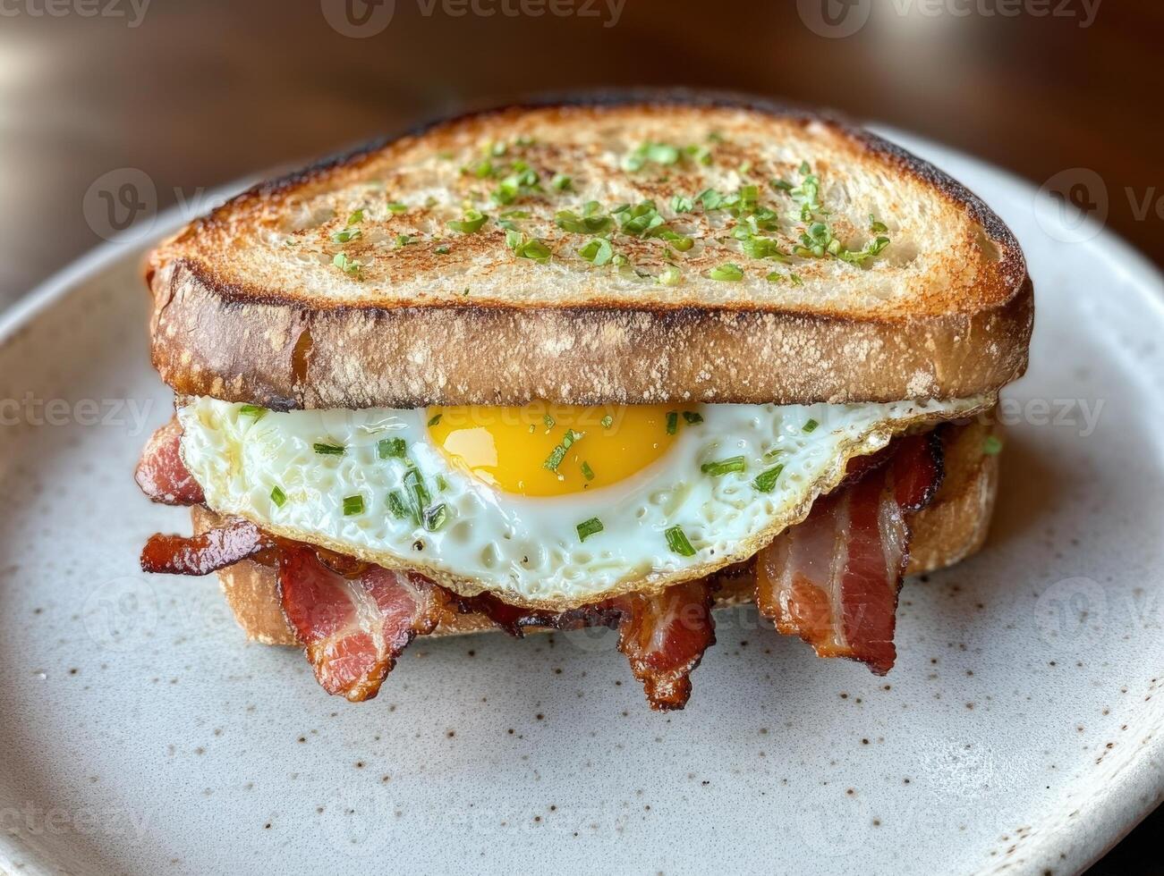 Breakfast sandwich with egg and bacon served on toasted bread photo