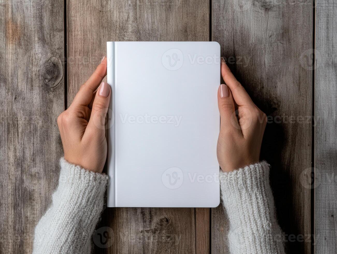 Hands holding a blank notebook on a rustic wooden surface photo