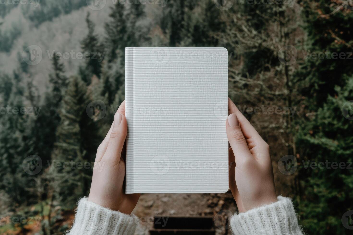 Hands hold a blank notebook in a forest setting photo