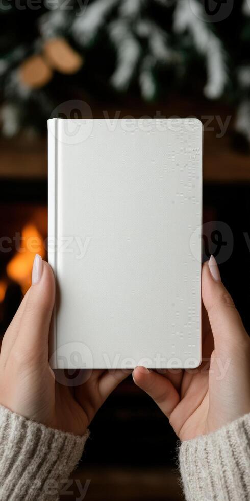 Hands holding a blank notebook in front of a cozy fireplace photo