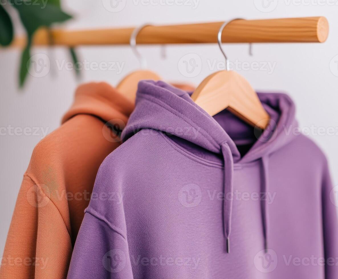 Two stylish hoodies displayed on a wooden hanger photo