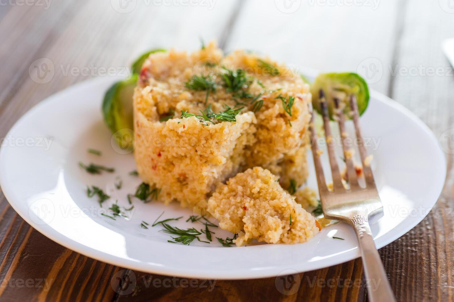 homemade cooked bulgur with Brussel sprouts in a plate, on a wooden table photo