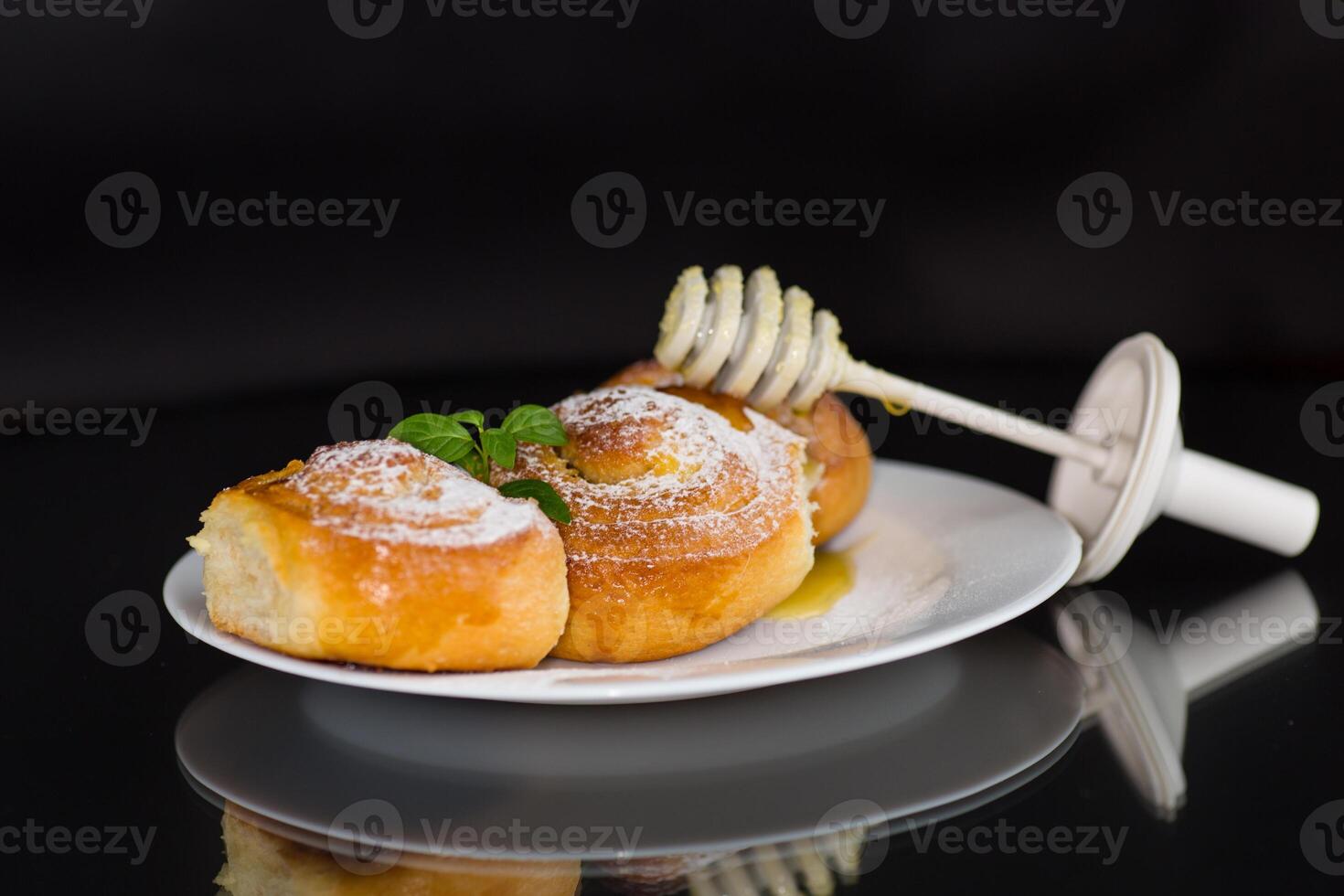 Baked goods. Sweet buns with cottage cheese filling and honey in a plate isolated on a black background photo