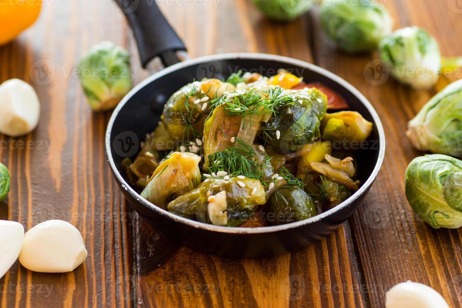 Brussel sprouts cooked with vegetables and spices, on a wooden table photo