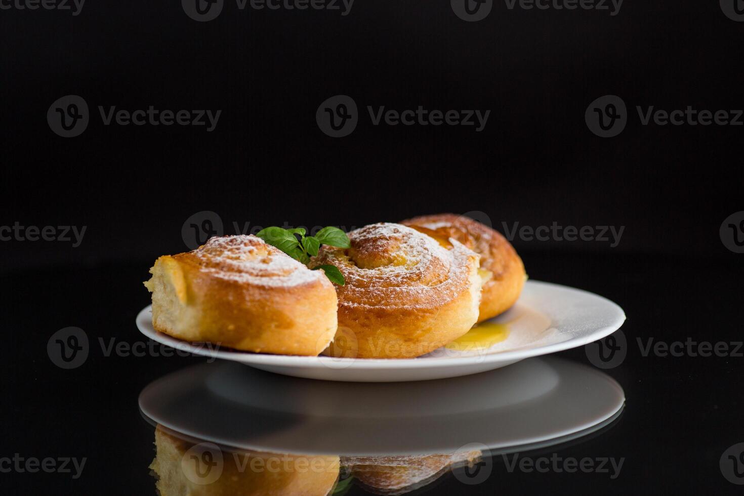 Baked goods. Sweet buns with cottage cheese filling and honey in a plate isolated on a black background photo