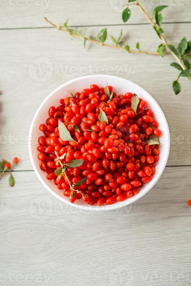 fresh ripe red goji berries in a bowl on a wooden table photo