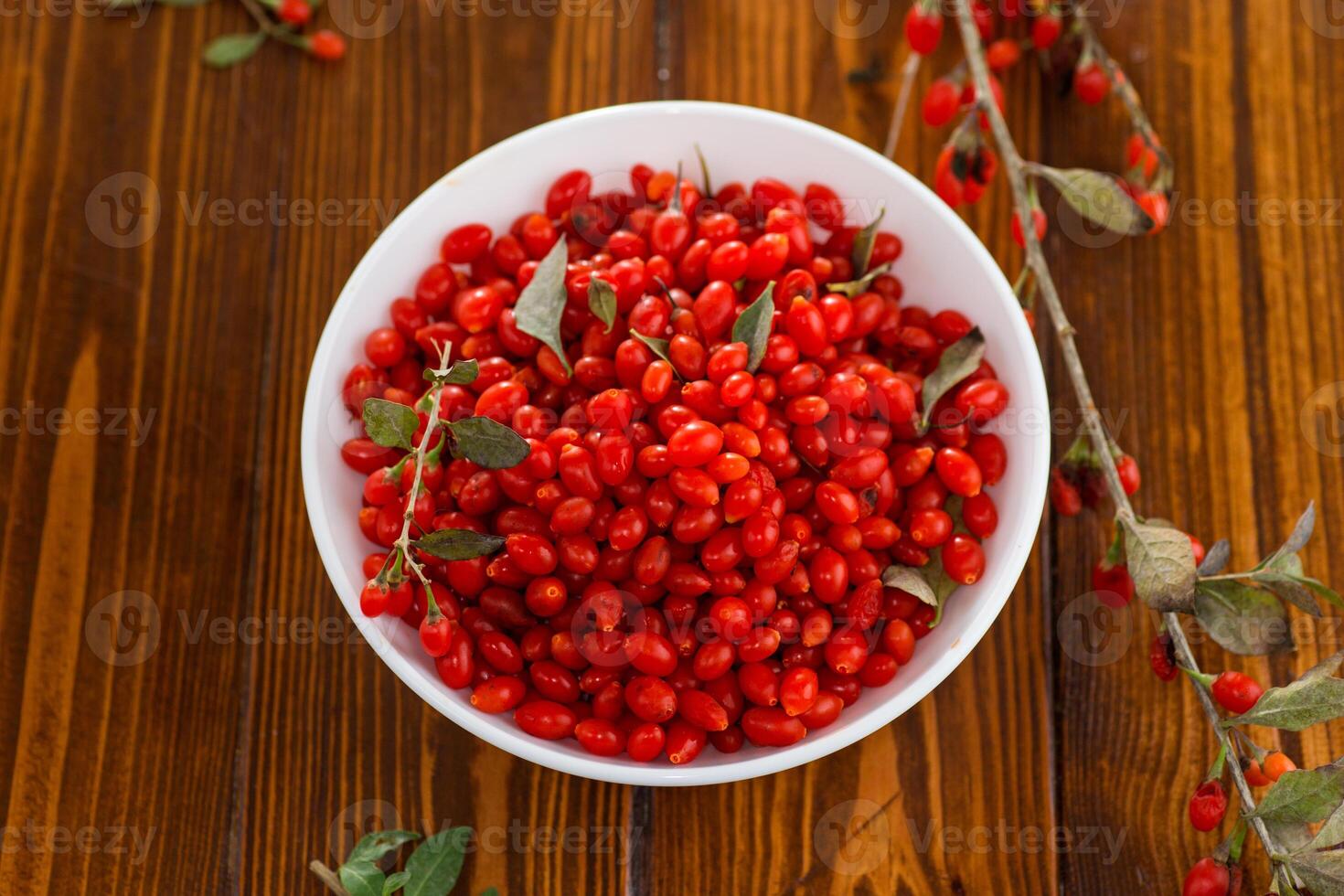 fresh ripe red goji berries in a bowl on a wooden table photo