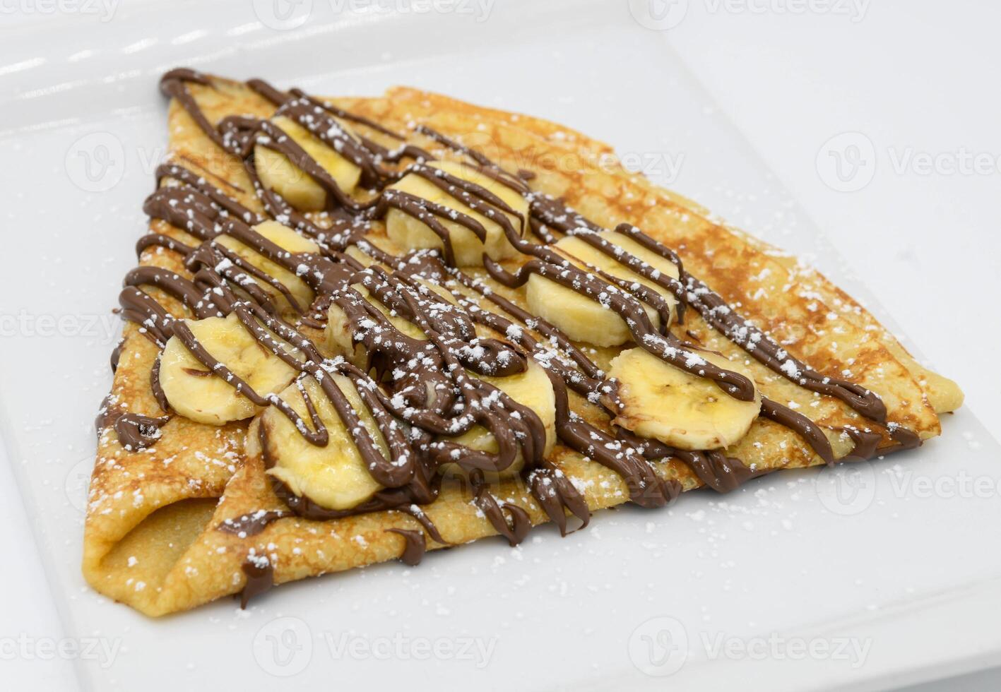 Pancakes with banana and chocolate on a white plate photo