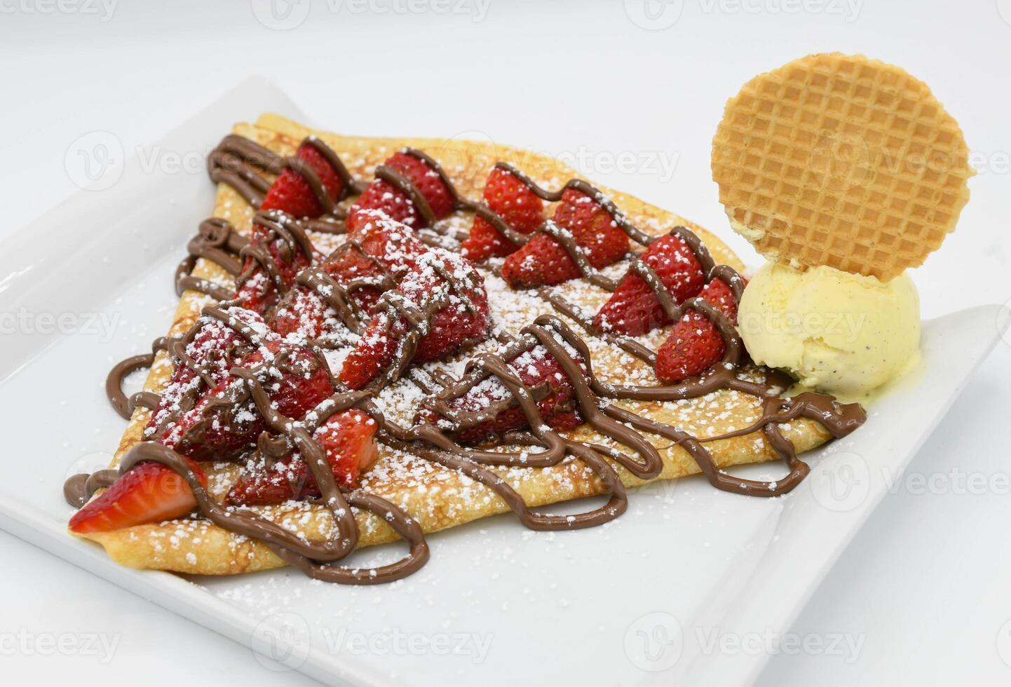 Crepe with strawberries and chocolate on a white plate. photo