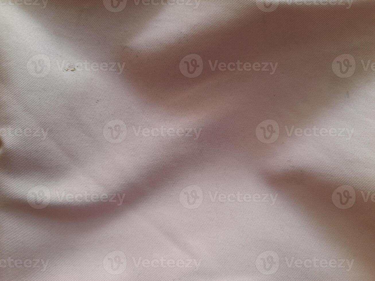a close-up view of a light-colored fabric with visible folds and subtle shadows, showcasing its texture and softness. photo
