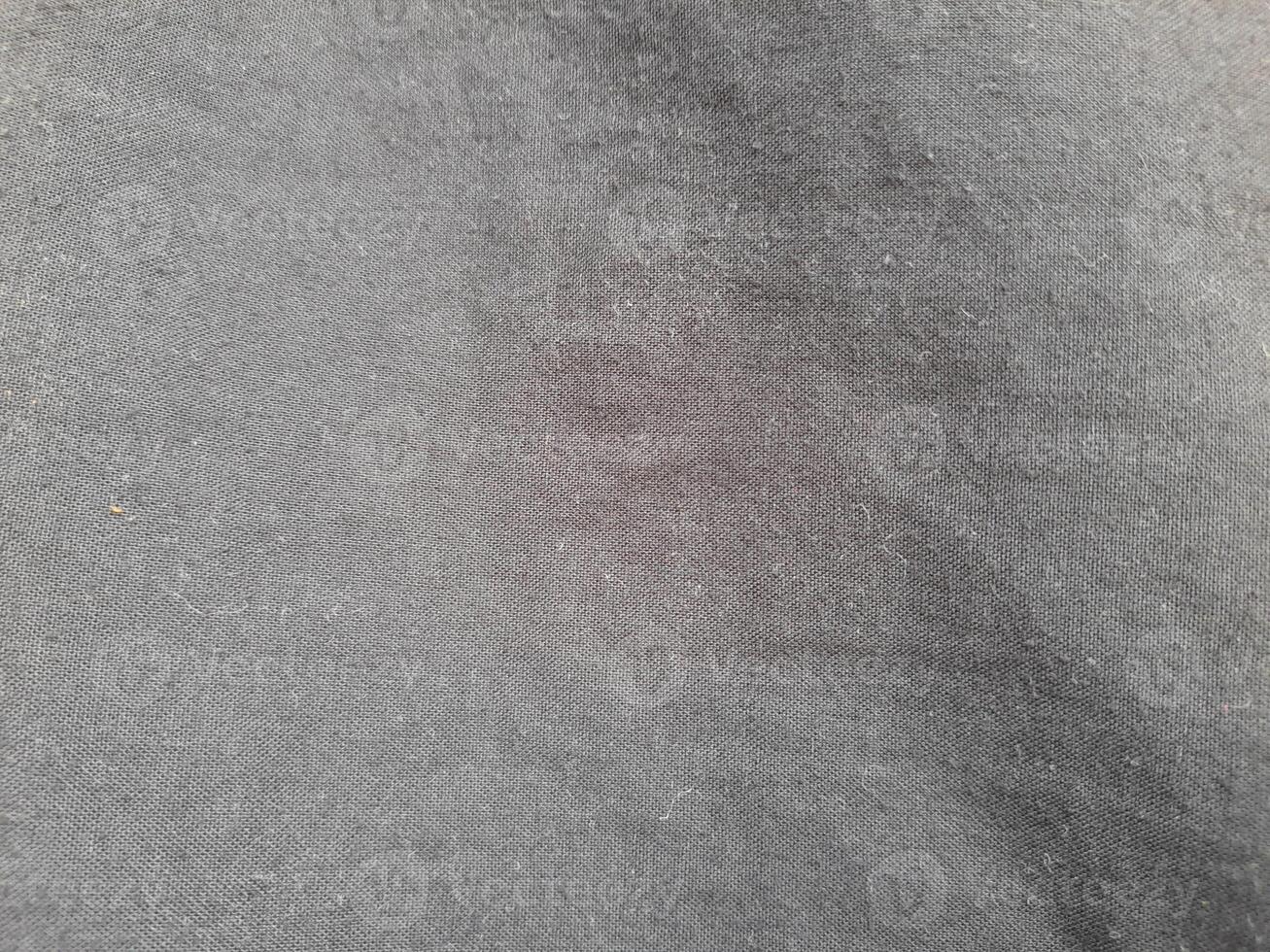 a close-up view of a smooth, black-colored fabric. The texture is fine and uniform, creating a soft and elegant appearance with no visible patterns or folds photo