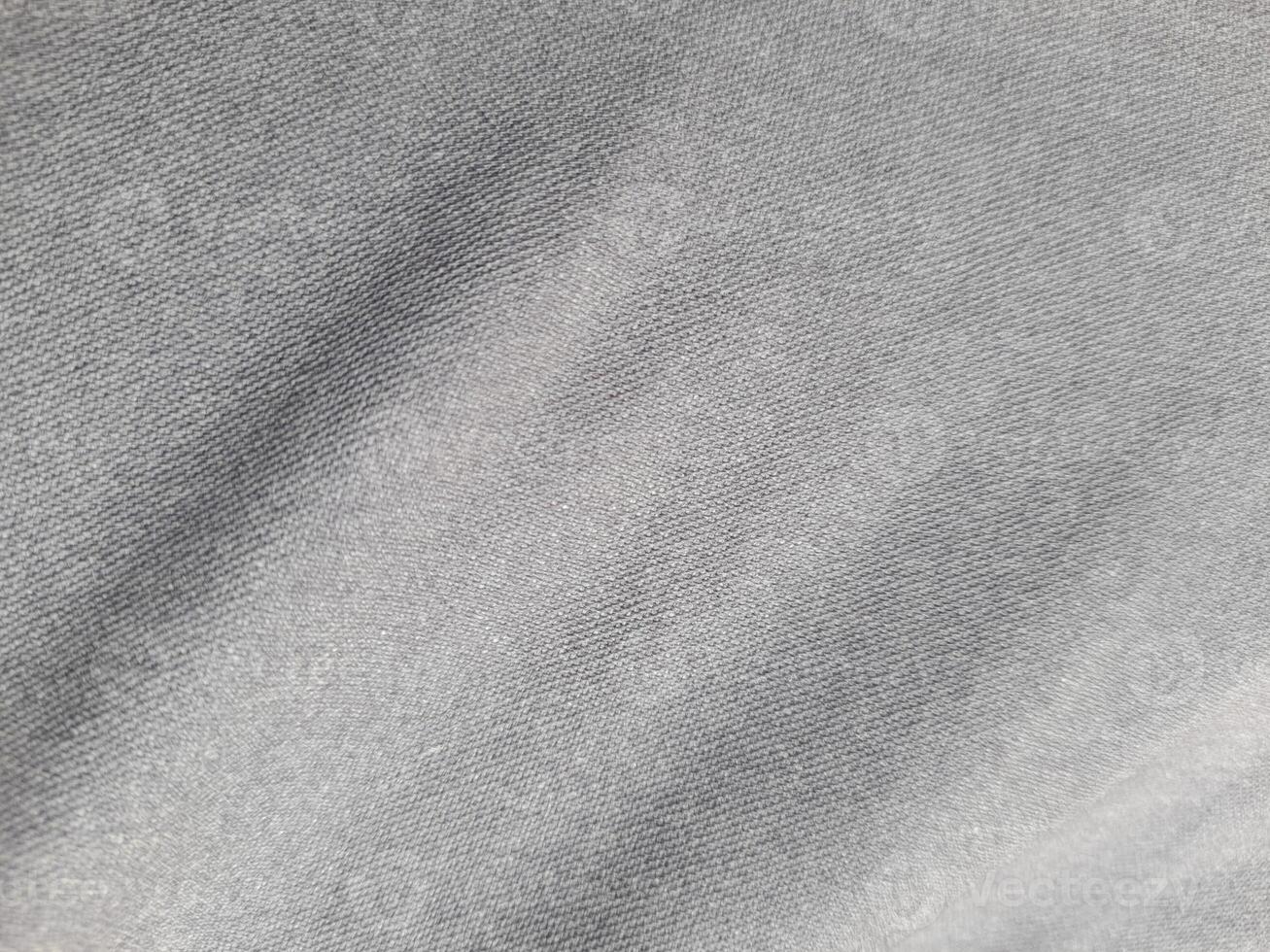 a close-up of a piece of gray fabric. The fabric appears to be woven, with a subtle texture visible in the weave. The color is a uniform, medium gray, with no discernible pattern or design. photo