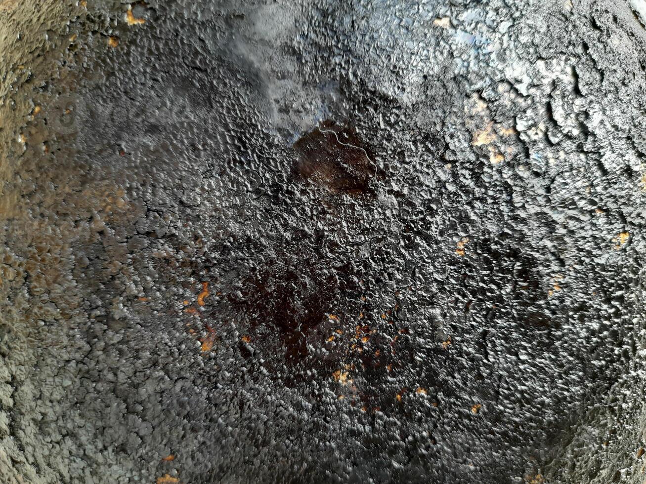 a heavily burned and blackened surface, a scorched pan or cooking utensil, with a textured and cracked appearance due to carbonized residue. photo