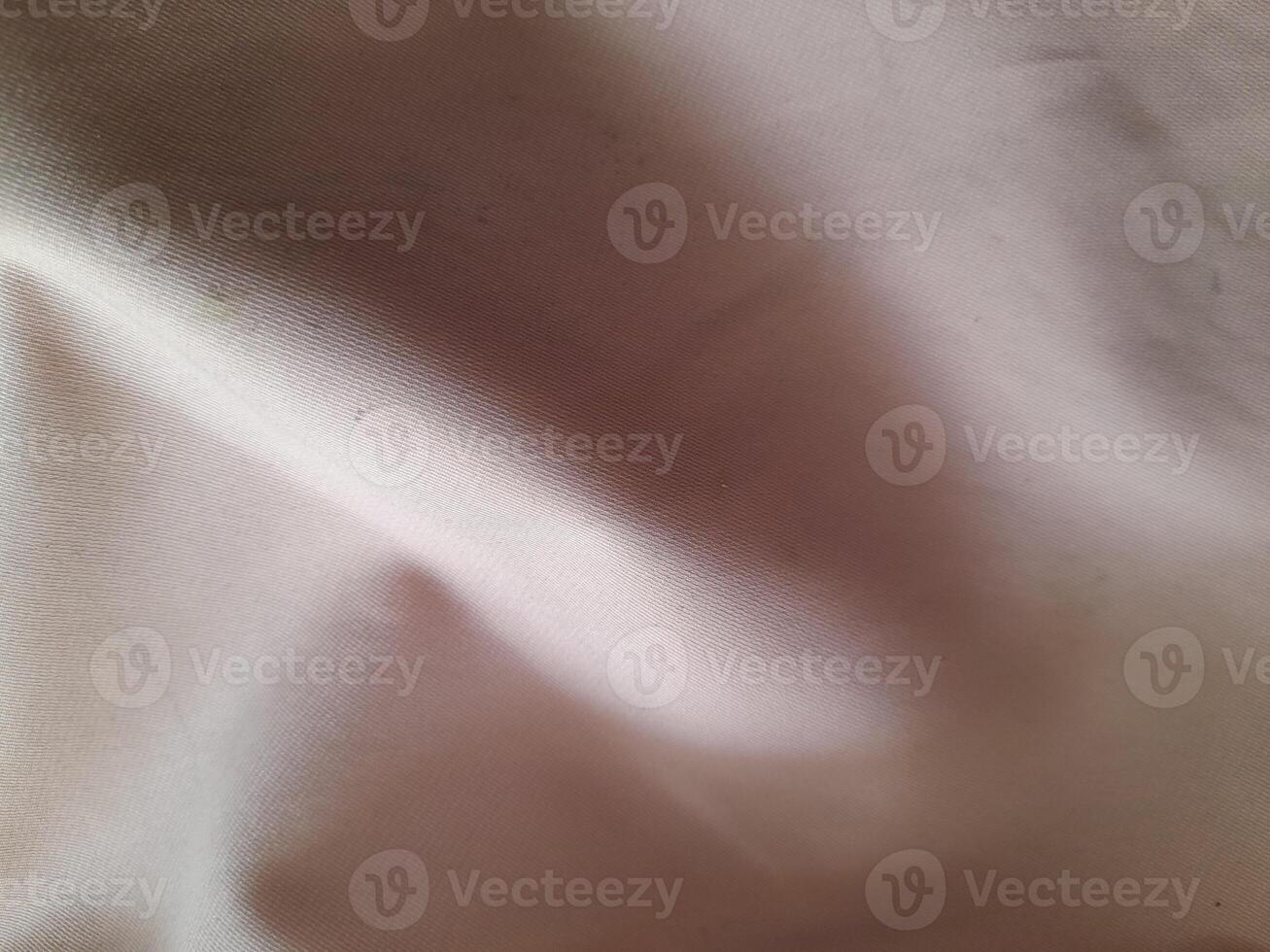 a close-up view of a light-colored fabric with visible folds and subtle shadows, showcasing its texture and softness. photo