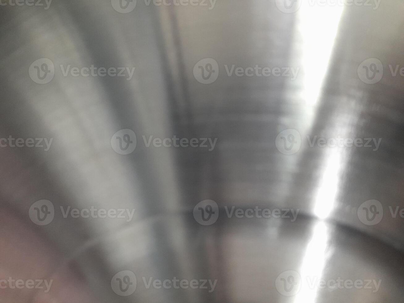 a close-up image of a brushed stainless steel surface. The circular brushing pattern is clearly visible, creating a textured appearance with fine lines radiating from the center. photo