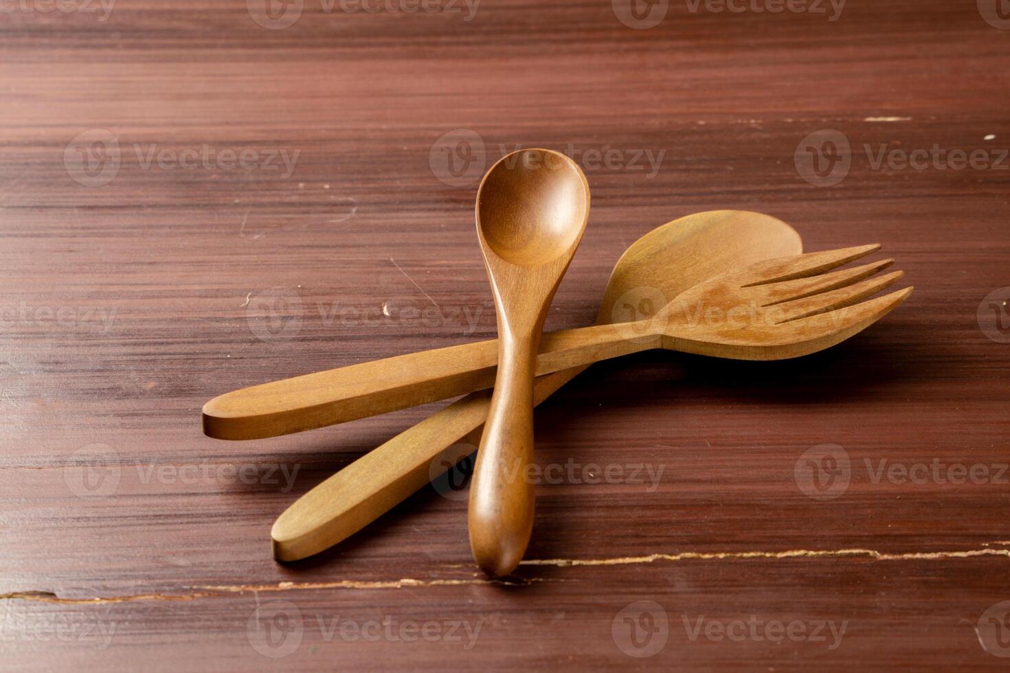 An isolated wooden spoon and fork placed on a wooden background, showcasing their natural texture and design. The simplicity of the scene highlights the rustic elegance photo