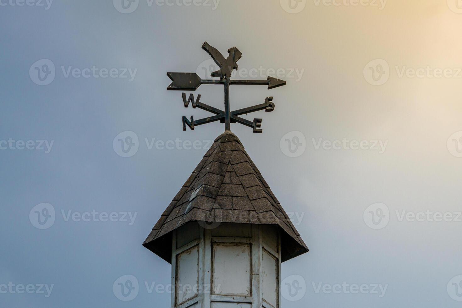 A wind vane on display with a stunning sky backdrop and rays of sunlight shining through. This image captures the beauty of the weather vane in a serene outdoor setting photo