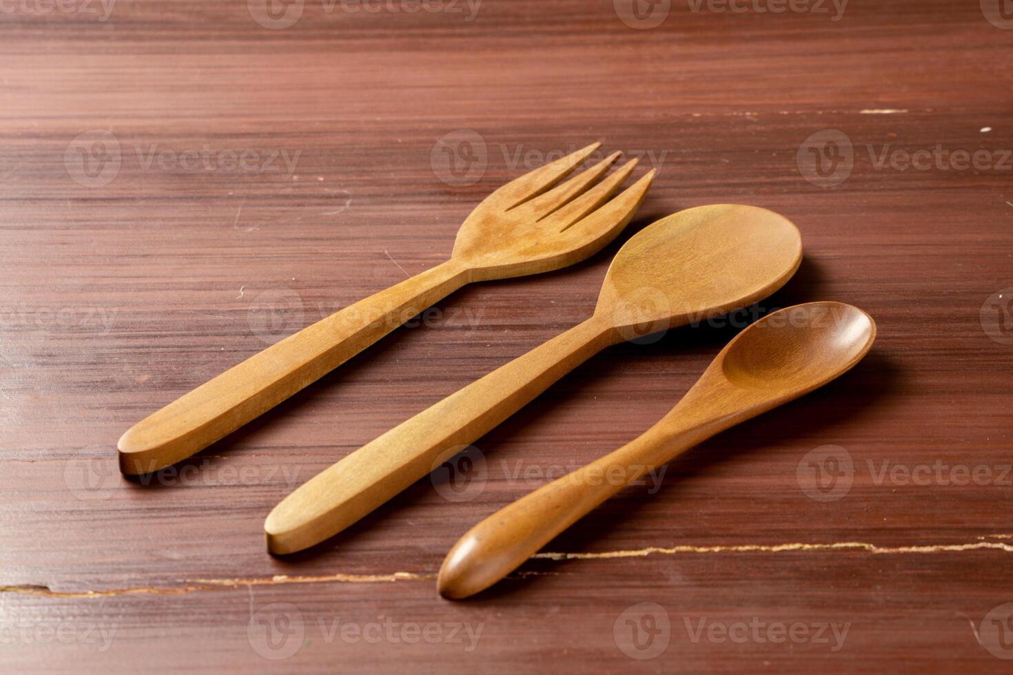 An isolated wooden spoon and fork placed on a wooden background, showcasing their natural texture and design. The simplicity of the scene highlights the rustic elegance photo