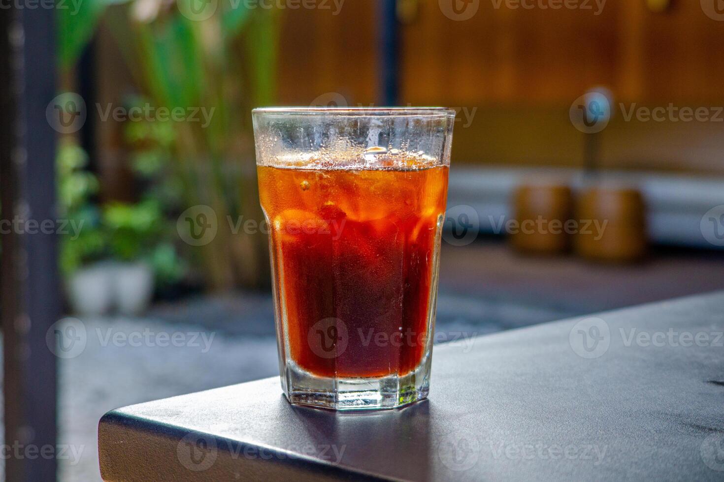 An iced americano served on a table at a coffee shop, with a cozy cafe ambience in the background. The cool beverage adds to the relaxed atmosphere of the cafe setting photo