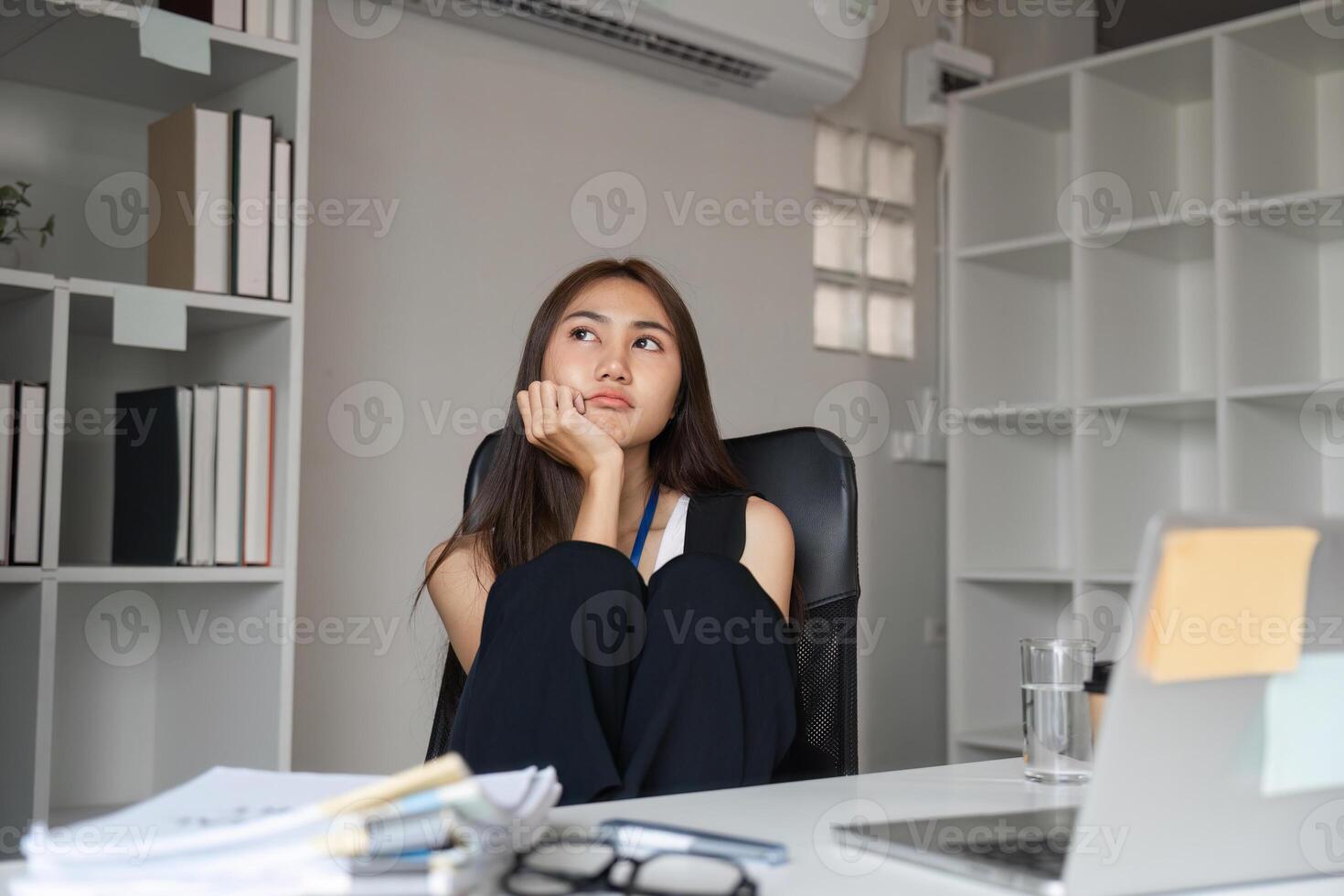 Bored Woman at Work Desk in Modern Office Setting with Laptop and Documents photo