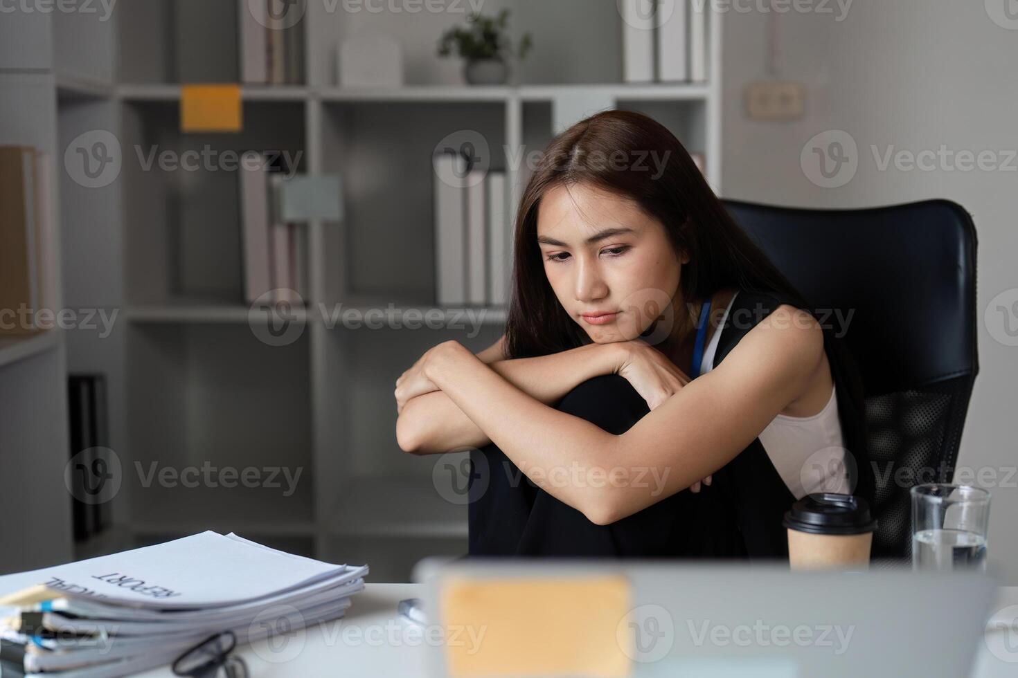 Bored Businesswoman at Office Desk with Laptop and Coffee, Feeling Uninspired and Unmotivated in Modern Workplace Environment photo