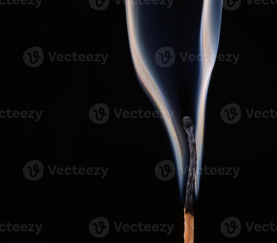 Burned match with clouds of smoke on a black background photo