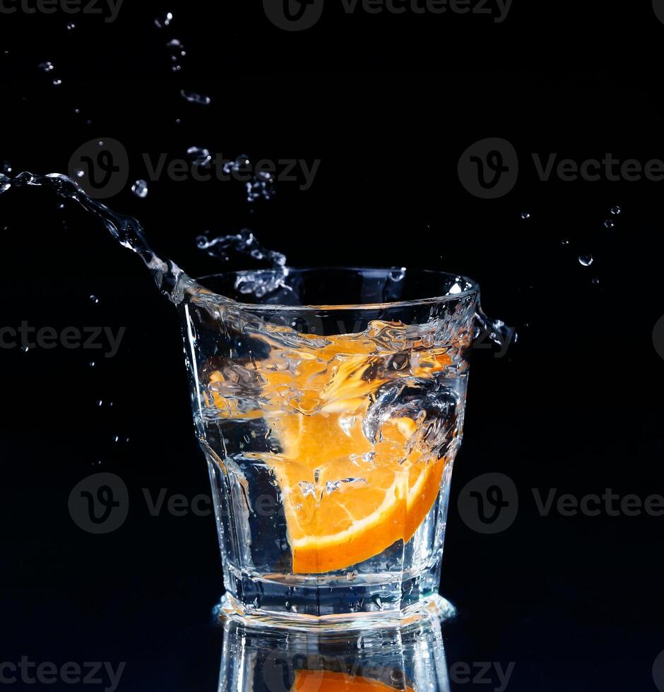 Slice of lemon splashing into a glass of water photo