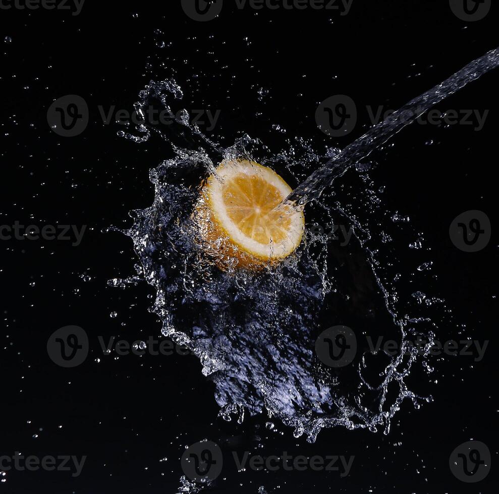 A high-speed shot of a lemon with splashing water, on a black background. photo