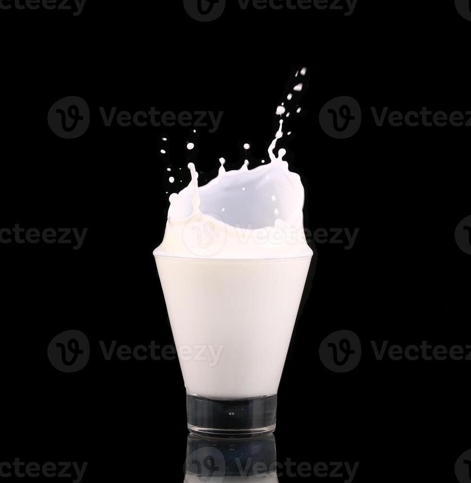Splash in a glass with milk isolated on black photo