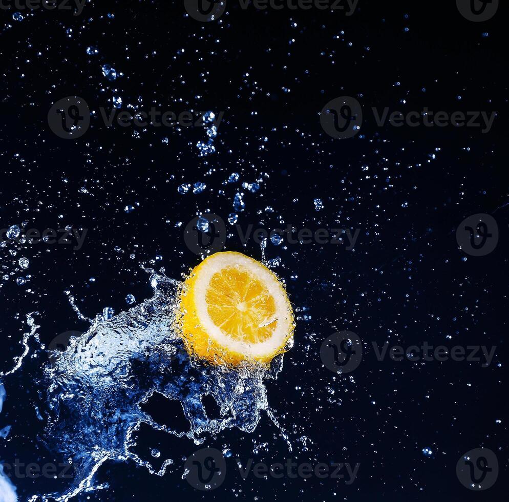 Lemon into water splash on black background photo