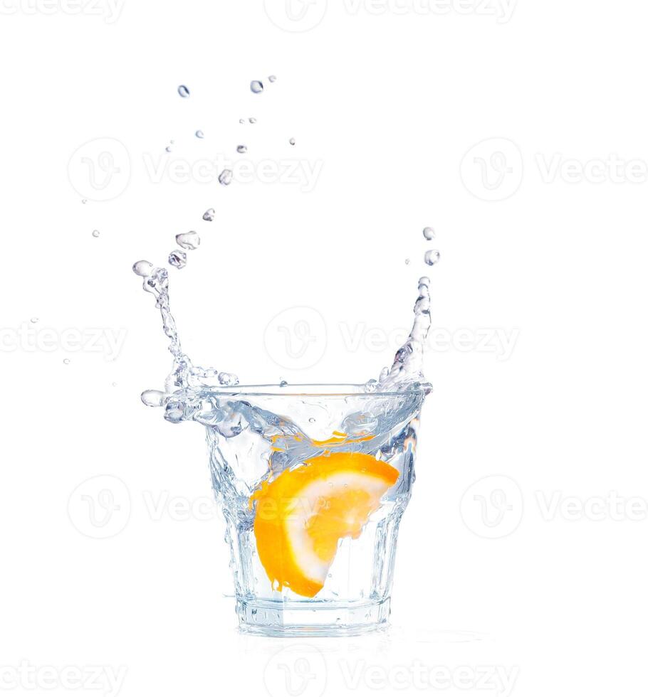 orange splashing into glass of water on white background photo