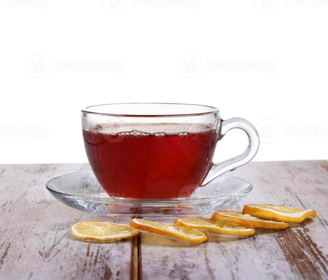 Glass cup with tea and a lemon on a glass saucer isolated on white background photo