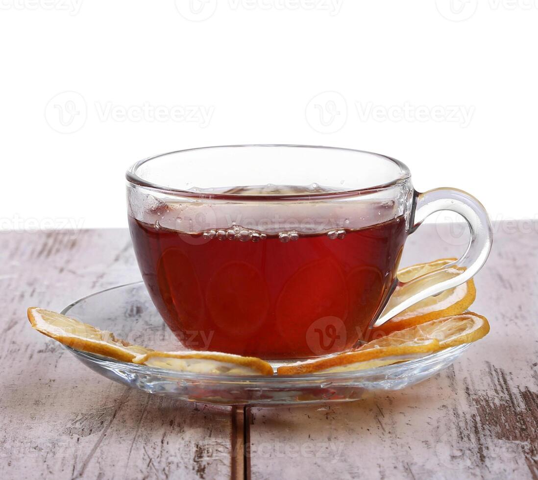 Glass cup with tea and a lemon on a glass saucer isolated on white background photo