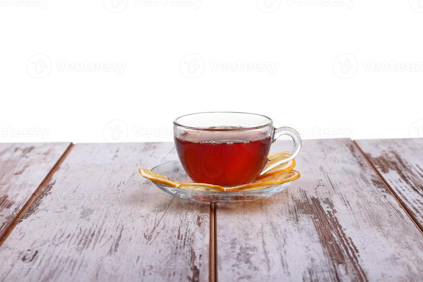 Glass cup with tea and a lemon on a glass saucer isolated on white background photo