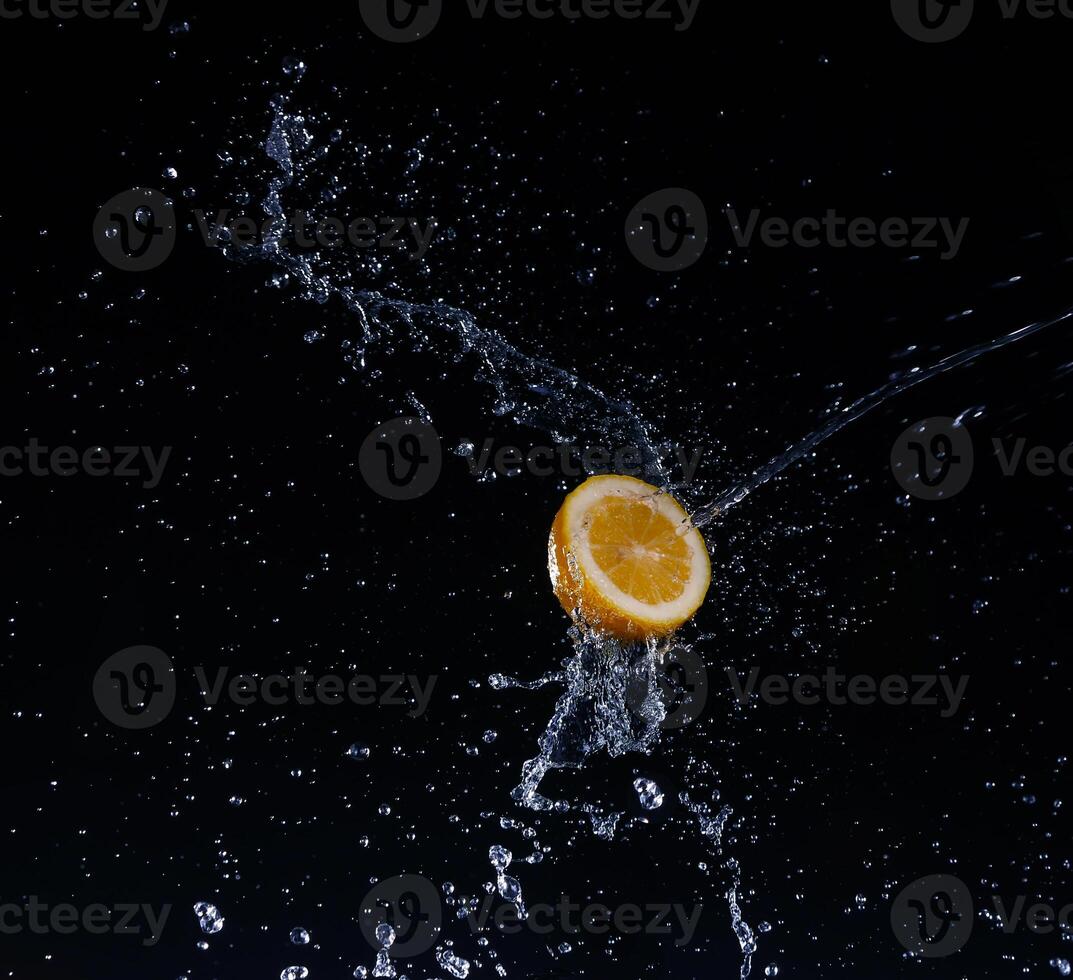 A high-speed shot of a lemon with splashing water, on a black background. photo