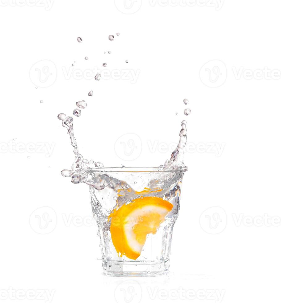 orange splashing into glass of water on white background photo