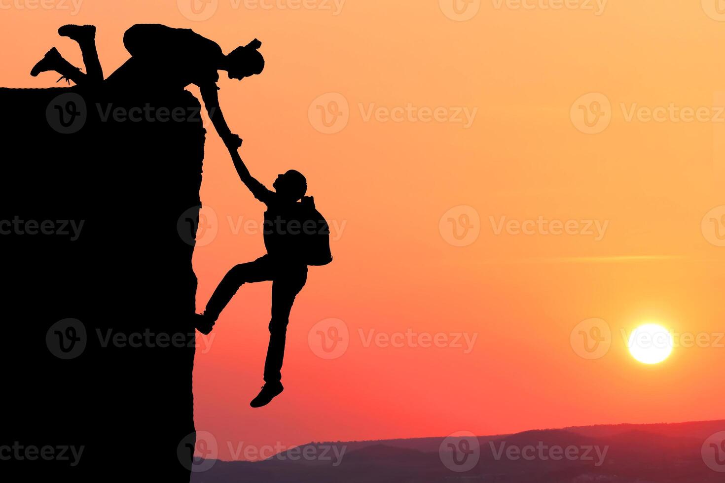 Teamwork couple hiking help each other trust assistance silhouette in mountains, sunset. Teamwork of man and woman hiker helping each other on top of mountain climbing team, beautiful sunset. photo