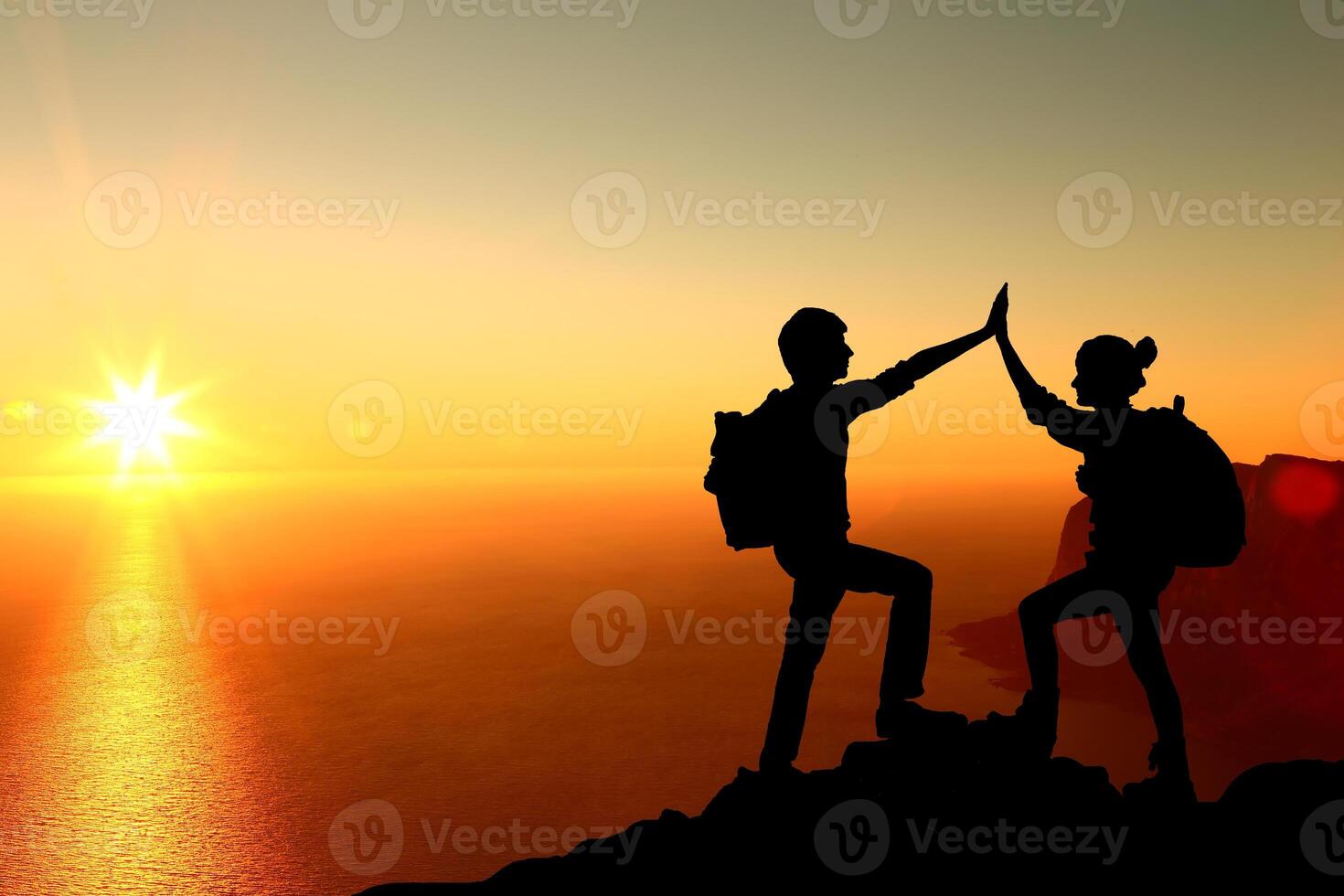 The Silhouette of two man with success gesture standing on the top of mountain photo