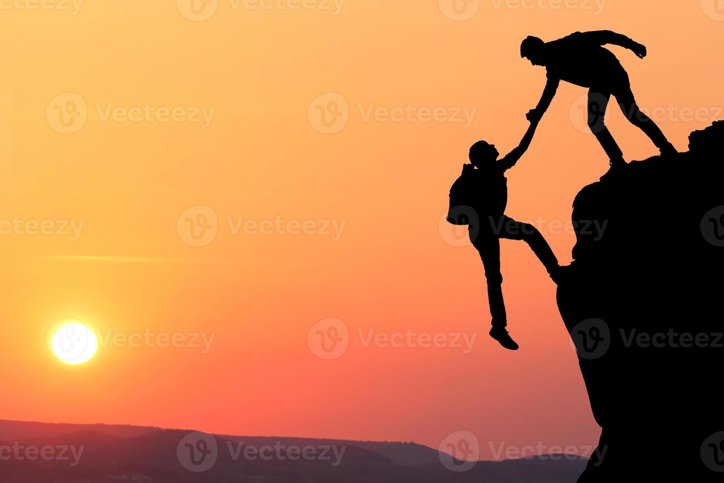 Teamwork couple hiking help each other trust assistance silhouette in mountains, sunset. Teamwork of two men hiker helping each other on top of mountain climbing team, beautiful sunset landscape. photo