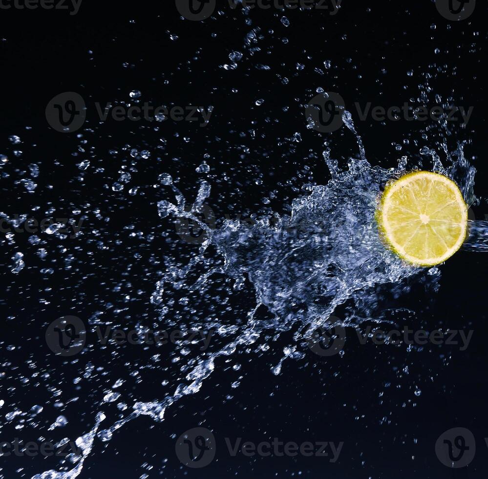 Half a lime falling into the water isolated on a black background photo