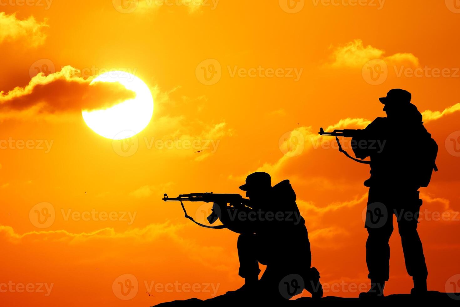 Silhouette shot of soldier holding gun with colorful sky and mountain in background photo
