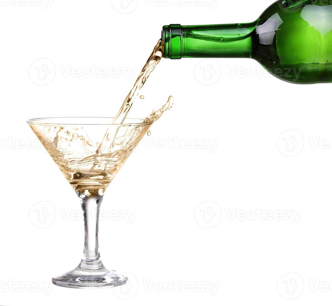 White wine pouring from the bottle intro the glass on white background photo