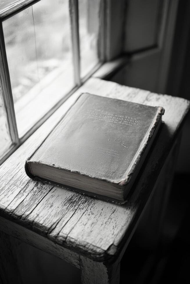 A weathered book resting on a rustic table near a window, capturing timeless beauty and history photo