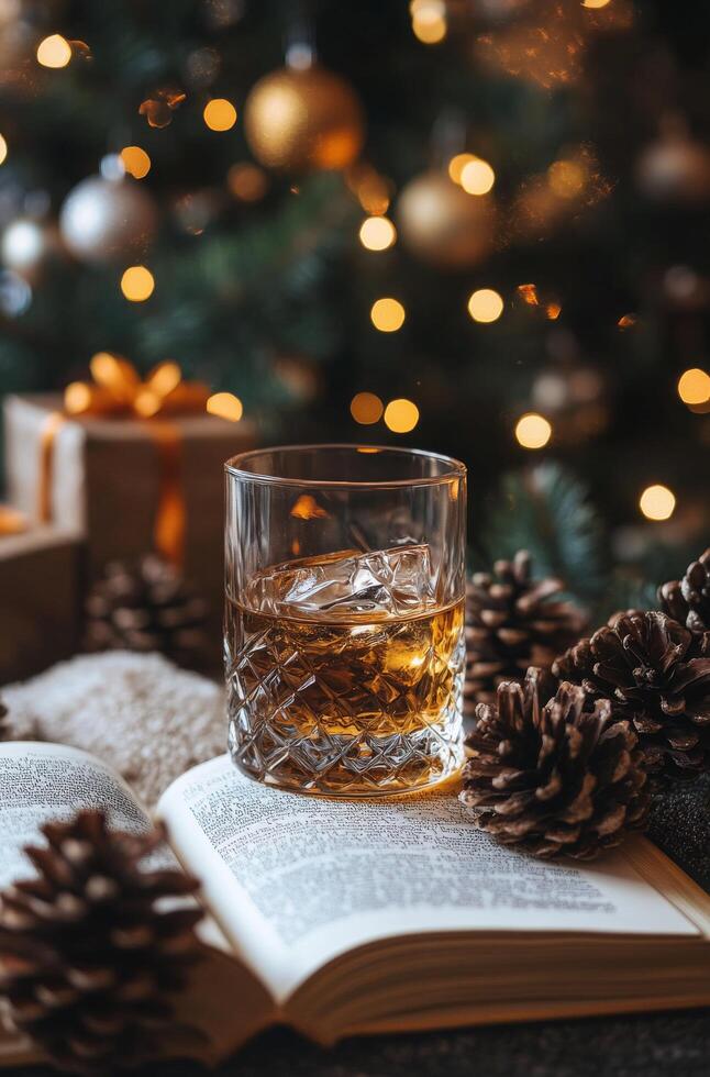 Glass of whiskey on an open book with pine cones and holiday gifts in the background photo