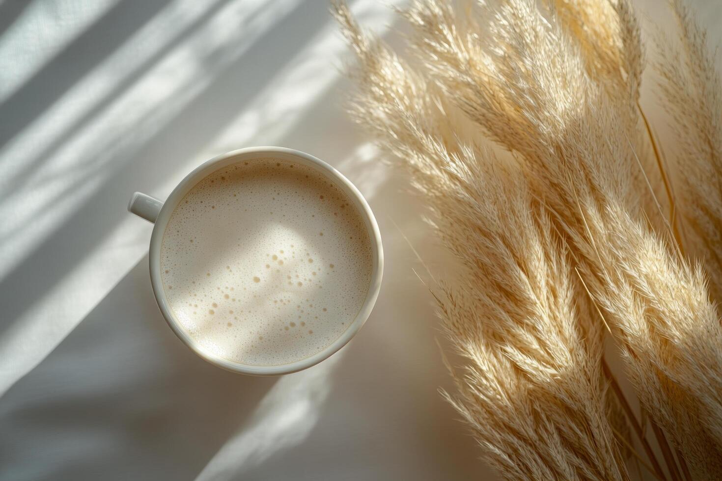 A cozy cup of cappuccino placed on a soft surface with dried grass in early morning light photo
