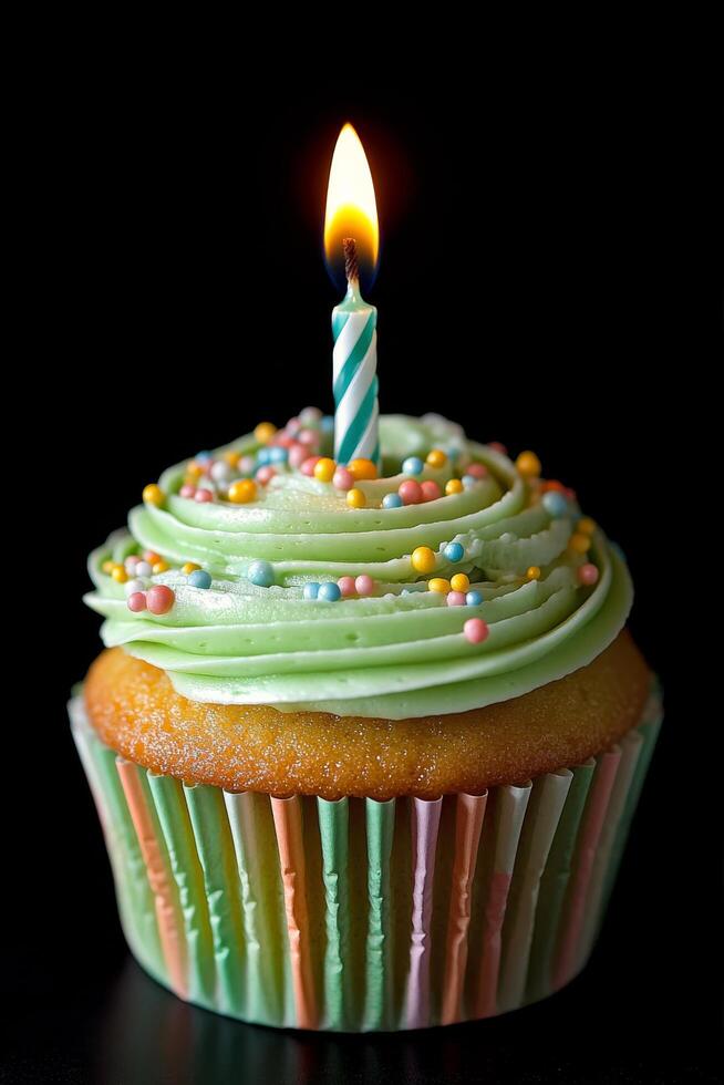 A beautifully decorated cupcake with green frosting and a birthday candle on top in a dark setting photo