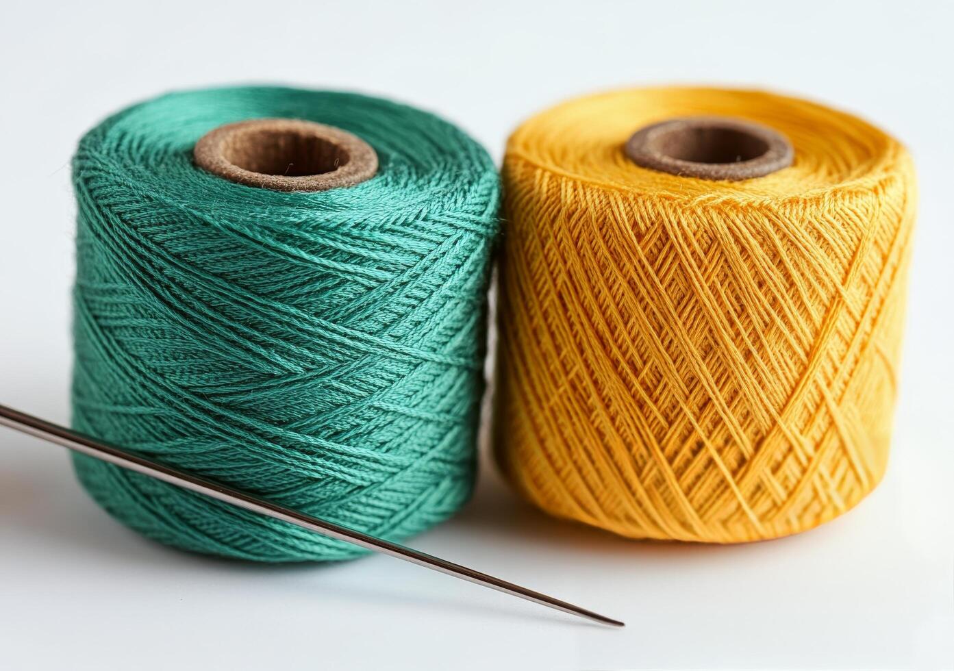 Spools of green and yellow thread with a sewing needle on a light background in a crafting workspace photo