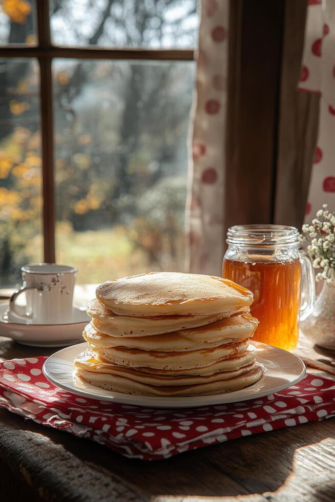 Stack of fluffy pancakes served with honey by a sunny window on a cozy autumn morning photo
